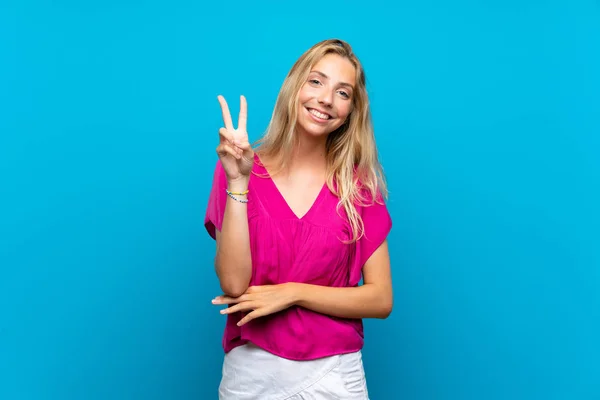 Блондинка Молода Жінка Над Ізольованим Синім Тлом Посміхається Показує Знак — стокове фото