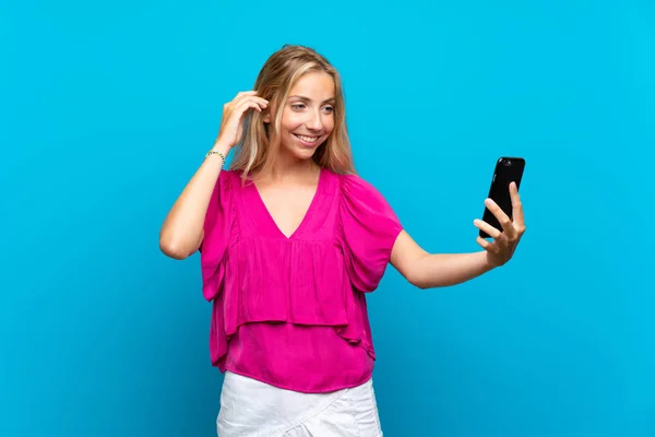 Mujer Joven Rubia Sobre Fondo Azul Aislado Haciendo Una Selfie —  Fotos de Stock