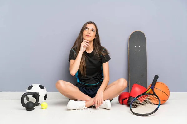 アイデアを考えて床に座っている若いスポーツ女性 — ストック写真