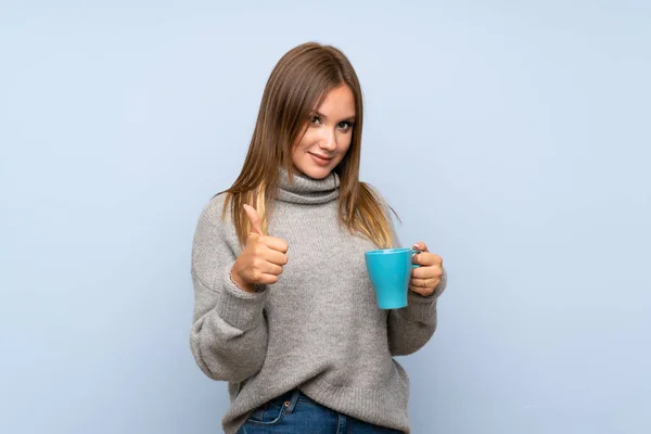 Teenager Mädchen Mit Pullover Über Isoliertem Blauem Hintergrund Hält Heiße — Stockfoto