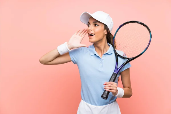 孤立したピンクの壁の上の若いテニスプレーヤーの女性は 口を大きく開いて叫ぶ — ストック写真