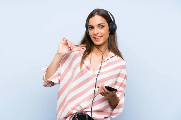 Jeune Femme Écoutant Musique Avec Mobile Sur Mur Bleu Isolé — Photo