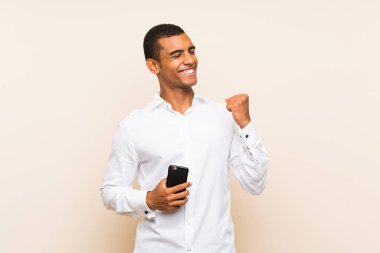 Zafer pozisyonunda telefon ile izole arka plan üzerinde Genç yakışıklı esmer adam