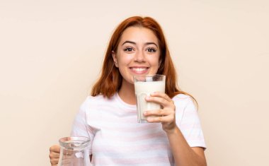 Genç kızıl saçlı kız izole arka plan üzerinde süt bir bardak tutan