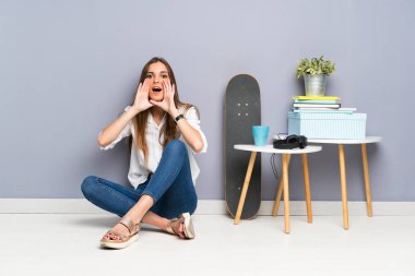 Genç bir kadın yerde oturuyor ve ağzı açık bağırıyor.