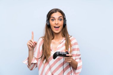 Genç kadın izole mavi duvar üzerinde bir video oyunu denetleyicisi ile oynayan harika bir fikir işaret