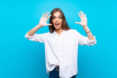 İzole mavi arka planda genç kadın parmak ile on sayma