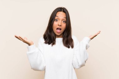 Sürpriz yüz ifadesi ile izole arka plan üzerinde beyaz kazak ile genç esmer kadın