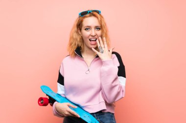 Sürpriz yüz ifadesi ile izole pembe arka plan üzerinde genç patenci kadın