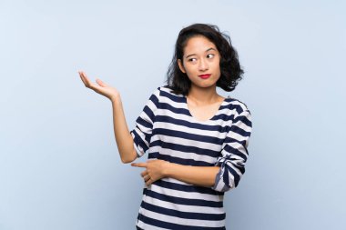 Izole mavi arka plan üzerinde Asyalı genç kadın bir şey anlamak için mutsuz