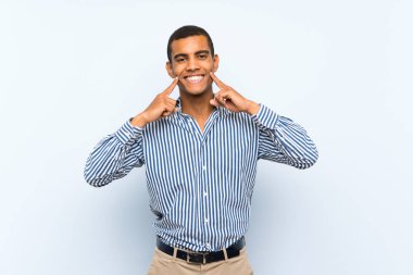 Izole mavi arka plan üzerinde genç yakışıklı esmer adam mutlu ve hoş bir ifade ile gülümseyen