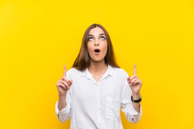 İşaret parmağı ile işaret izole sarı arka plan üzerinde genç kadın harika bir fikir