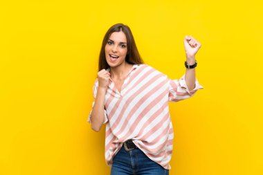 Sarı arka planda zafer kutlaması yapan genç bir kadın.