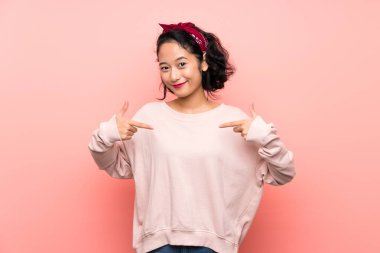 Izole pembe arka plan üzerinde Asyalı genç kadın gururlu ve kendini tatmin