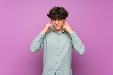Izole mor duvar üzerinde genç adam sinirli ve kulakları kapsayan
