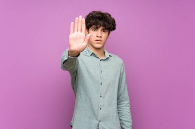 Izole mor duvar üzerinde genç adam stop jest yapma