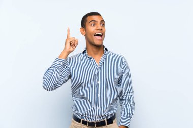 Izole mavi arka plan üzerinde genç yakışıklı esmer adam bir parmak kaldırırken çözüm gerçekleştirmek niyetinde