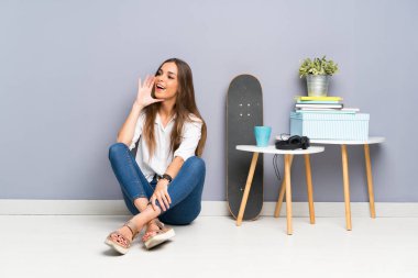 Genç bir kadın yerde oturuyor ve ağzı açık bağırıyor.