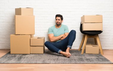 Yakışıklı genç adam kutuları arasında yeni bir evde bir fikir düşünme hareketli