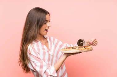 İzole pembe duvar üzerinde pizza tutan genç kadın