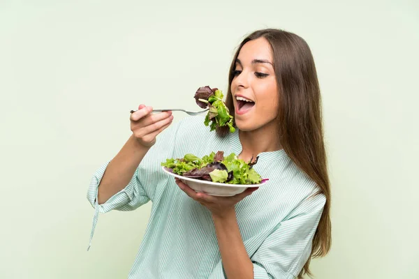 Mujer joven con ensalada sobre pared verde aislada — Foto de Stock