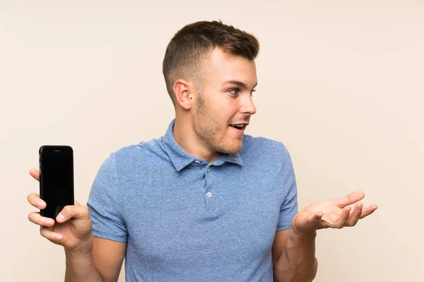 Joven Hombre Rubio Usando Teléfono Móvil Con Expresión Facial Sorpresa —  Fotos de Stock