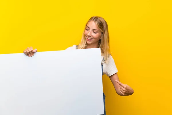 Jovem Loira Sobre Fundo Amarelo Isolado Segurando Cartaz Branco Vazio — Fotografia de Stock