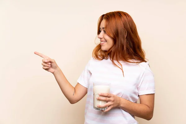 Menina Ruiva Adolescente Segurando Copo Leite Sobre Fundo Isolado Apontando — Fotografia de Stock