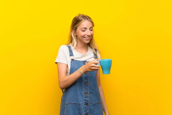Loira Jovem Sobre Isolado Fundo Amarelo Segurando Xícara Quente Café — Fotografia de Stock