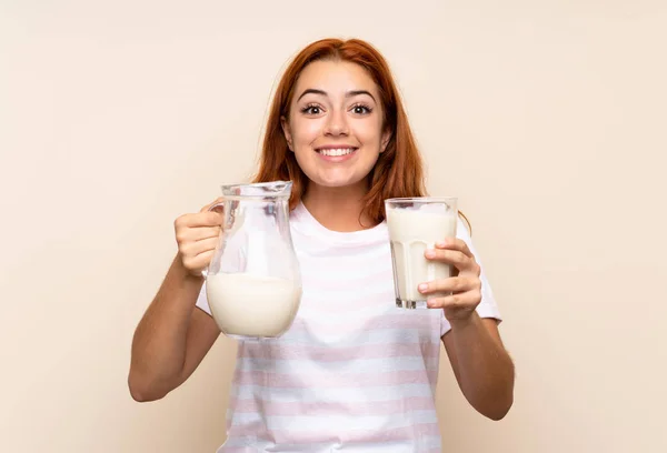 Adolescente pelirroja sosteniendo un vaso de leche sobre un fondo aislado — Foto de Stock