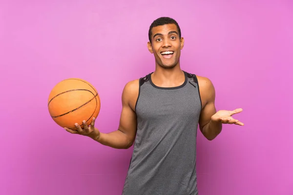 Молодой Спортсмен Мячом Баскетбола Над Изолированной Фиолетовой Стеной Шокированным Лицом — стоковое фото