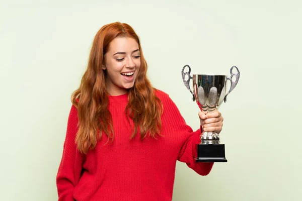 Adolescente Rossa Ragazza Con Maglione Sfondo Verde Isolato Possesso Trofeo — Foto Stock