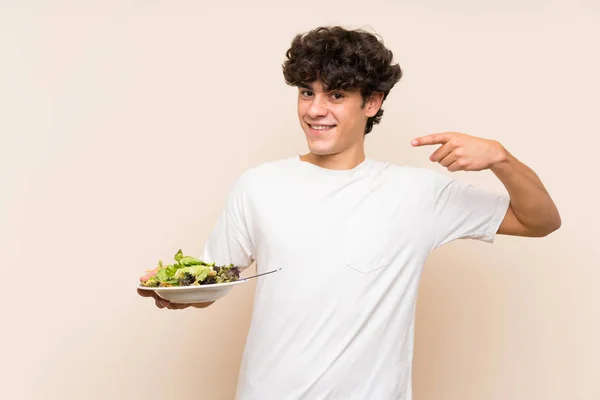 Joven con ensalada sobre pared verde aislada —  Fotos de Stock