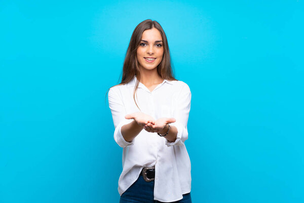 Молодая женщина на изолированном синем фоне держит копирайт воображаемого на ладони, чтобы вставить объявление