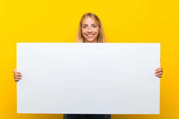 金发年轻女子在孤立的黄色背景拿着一个空的白色标语牌插入一个概念 — 图库照片