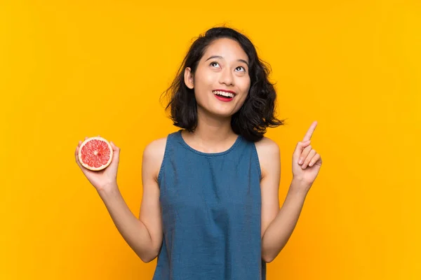 Ung Asiatisk Tjej Som Håller Grapefrukt Över Isolerad Orange Bakgrund — Stockfoto