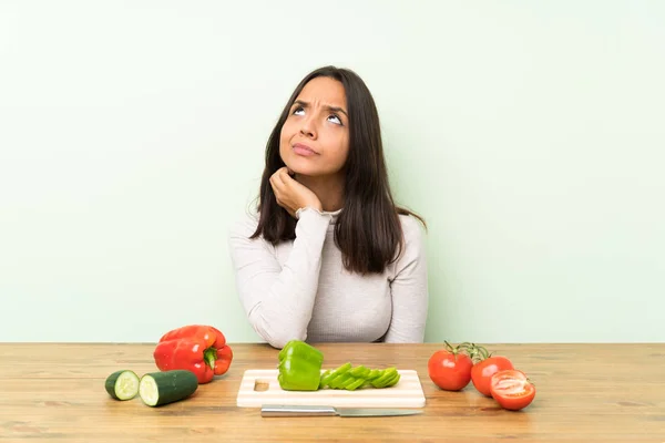 Young brunette woman with vegetables thinking an idea