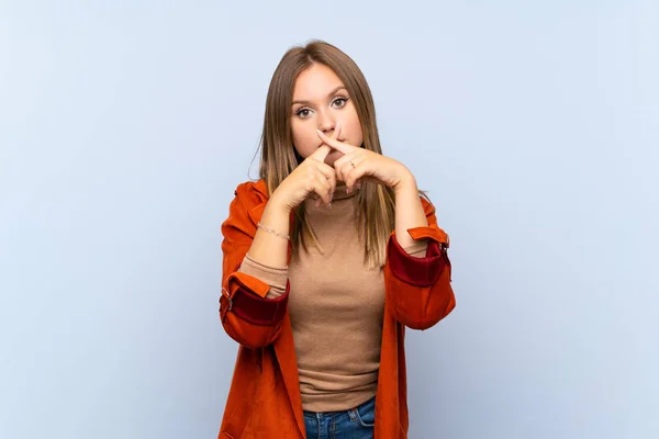 Teenagerka Kabátem Přes Izolované Modré Pozadí Ukazující Znamení Ticha — Stock fotografie