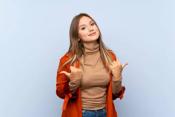 Teenager Mädchen Mit Mantel Über Isoliertem Blauem Hintergrund Mit Daumen — Stockfoto