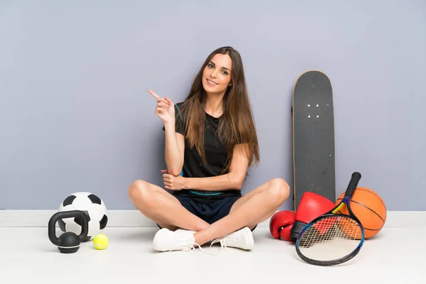 Молода Спортивна Жінка Сидить Підлозі Вказуючи Пальцем Бік — стокове фото