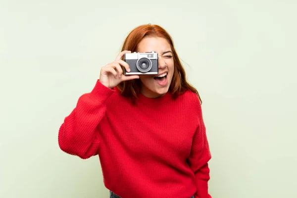 Adolescente Pelirroja Con Suéter Sobre Fondo Verde Aislado Sosteniendo Una —  Fotos de Stock