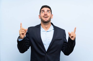 Izole mavi arka plan üzerinde Yakışıklı adam şaşırttı ve işaret