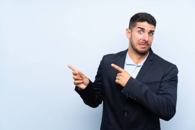 Izole mavi arka plan üzerinde Yakışıklı adam korkmuş ve yan işaret