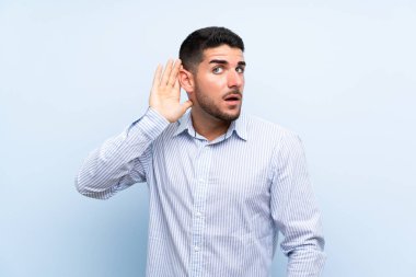 Izole mavi arka plan üzerinde Kafkas yakışıklı adam bir şey dinlerken