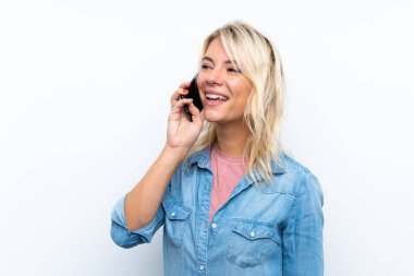 İzole edilmiş beyaz arka planda genç sarışın kadın cep telefonuyla sohbet ediyor.