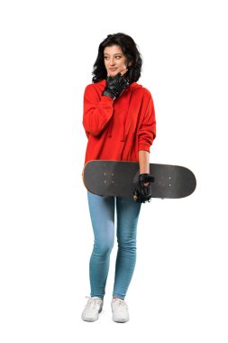 Genç bir patenci kadının izole edilmiş beyaz bir arka plan üzerinde düşündüğü uzun bir çekim.