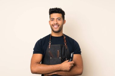 Kuaför veya berber elbisesi ile izole arka plan üzerinde genç yakışıklı adam ve saç kesme makinesi tutarak