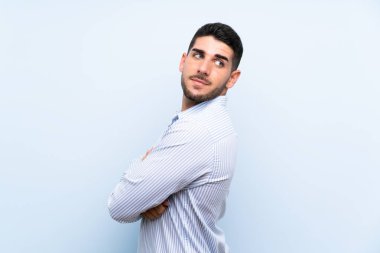 Kafkasyalı yakışıklı adam soyutlanmış mavi arka planda gülüyor.