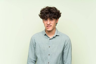 Izole yeşil duvar üzerinde genç adam şüpheleri olan ve yüz ifadesi karıştırmayın