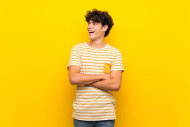 Izole sarı duvar üzerinde genç adam mutlu ve gülümseyerek